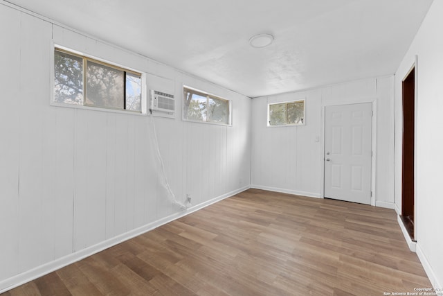 empty room with a wall unit AC, a wealth of natural light, and light hardwood / wood-style flooring