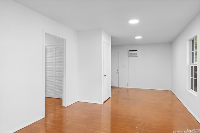 spare room featuring a wall mounted AC and light wood-type flooring