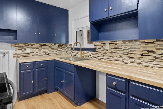 kitchen featuring blue cabinetry, butcher block counters, light hardwood / wood-style flooring, and sink