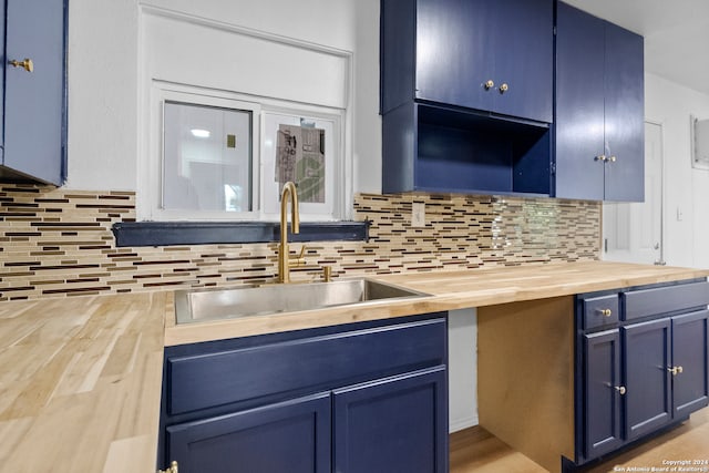 kitchen with sink, tasteful backsplash, blue cabinetry, and wooden counters