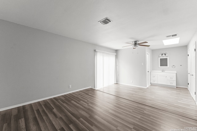 unfurnished living room featuring a skylight, ceiling fan, hardwood / wood-style floors, and sink