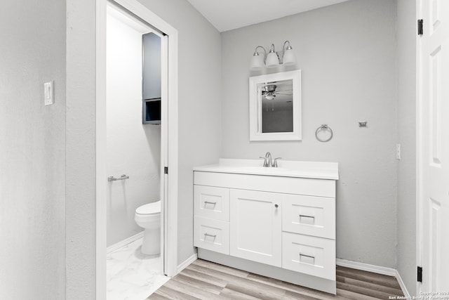 bathroom featuring hardwood / wood-style flooring, vanity, ceiling fan, and toilet