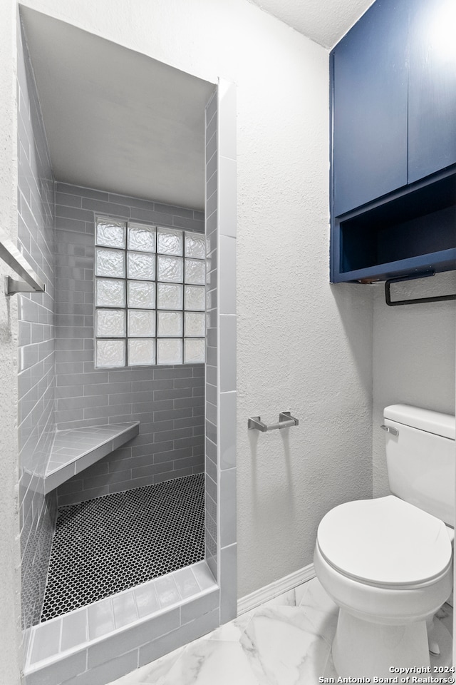 bathroom featuring a tile shower and toilet