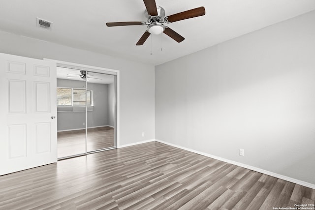 unfurnished bedroom with hardwood / wood-style floors, ceiling fan, and a closet