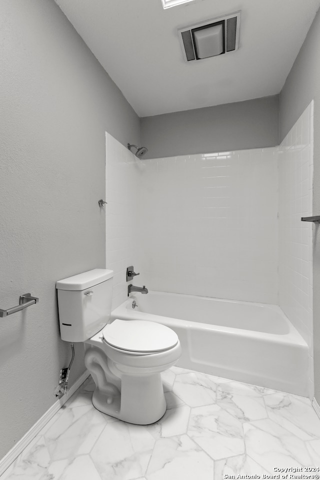 bathroom with toilet and tiled shower / bath