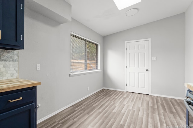 interior space featuring wood counters, light hardwood / wood-style flooring, lofted ceiling, and blue cabinets