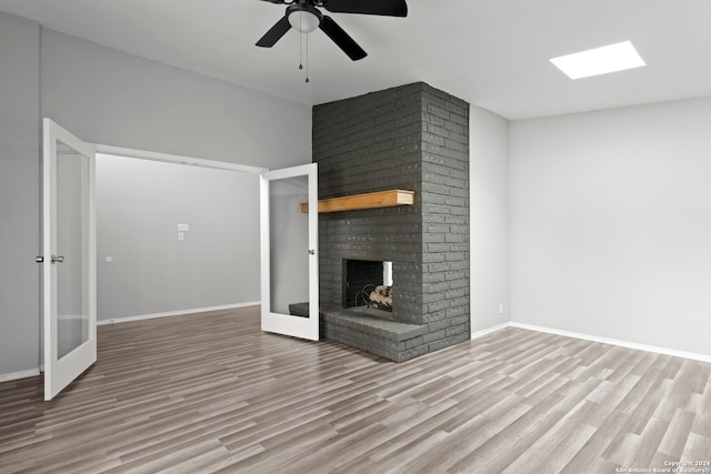 unfurnished living room featuring ceiling fan, light wood-type flooring, a fireplace, and french doors