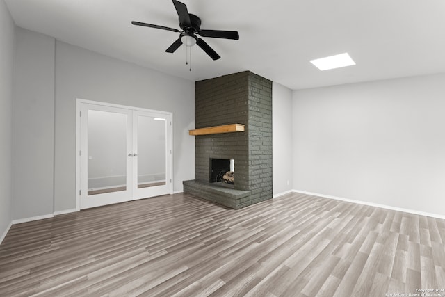 unfurnished living room with ceiling fan, light hardwood / wood-style floors, and a brick fireplace