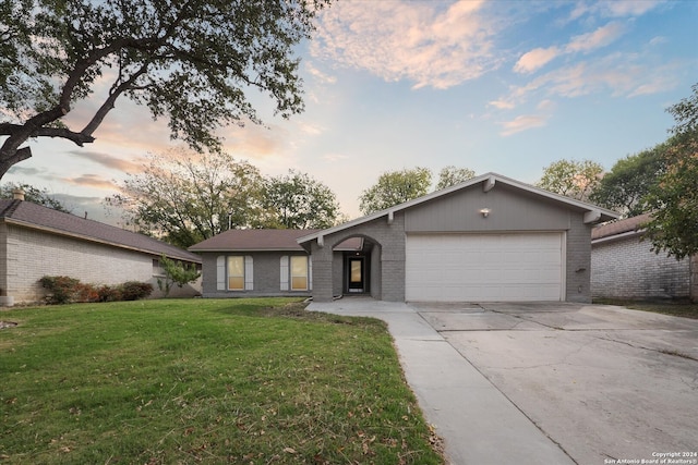 ranch-style home featuring a garage and a lawn