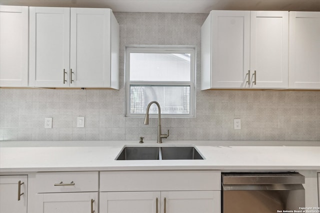 kitchen featuring white cabinetry, stainless steel dishwasher, tasteful backsplash, and sink