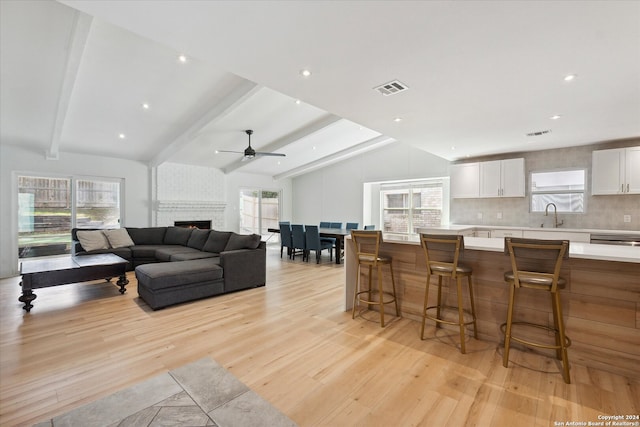 living room with lofted ceiling with beams, a healthy amount of sunlight, and light wood-type flooring