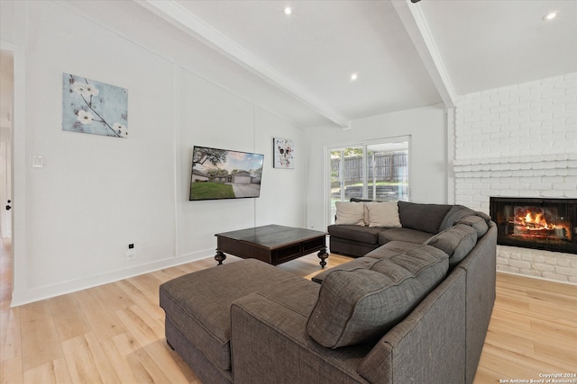 living room featuring a brick fireplace, vaulted ceiling with beams, and light hardwood / wood-style flooring