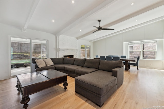 living room featuring a brick fireplace, ceiling fan, plenty of natural light, and light wood-type flooring