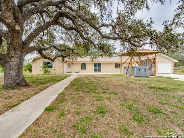 ranch-style house featuring a front yard, a hot tub, and a garage