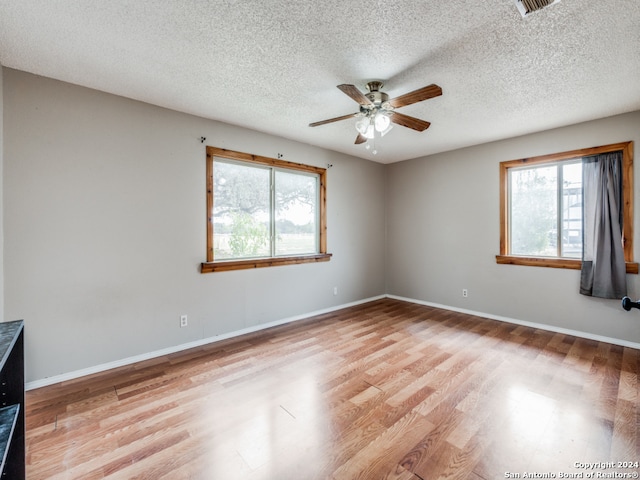 spare room with light hardwood / wood-style flooring, a healthy amount of sunlight, and a textured ceiling