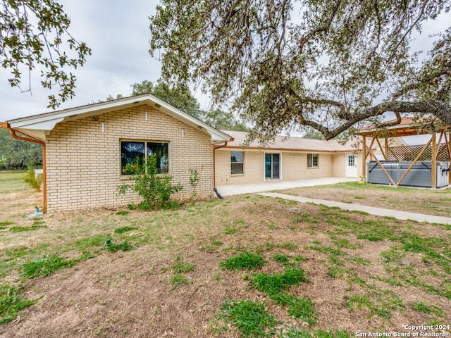 rear view of property featuring a patio area and a hot tub