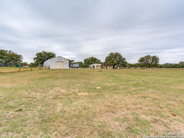 view of yard featuring a rural view, an outdoor structure, and a garage