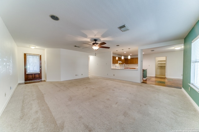 unfurnished living room with ceiling fan and light carpet