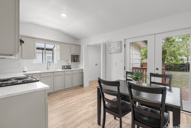 kitchen with plenty of natural light, lofted ceiling, sink, and light hardwood / wood-style flooring