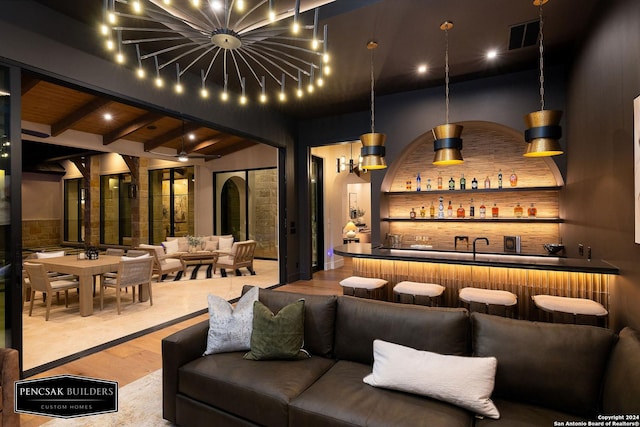 bar featuring beamed ceiling, light hardwood / wood-style floors, and decorative light fixtures