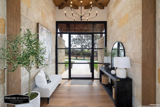 entryway with beamed ceiling, a towering ceiling, hardwood / wood-style flooring, and an inviting chandelier