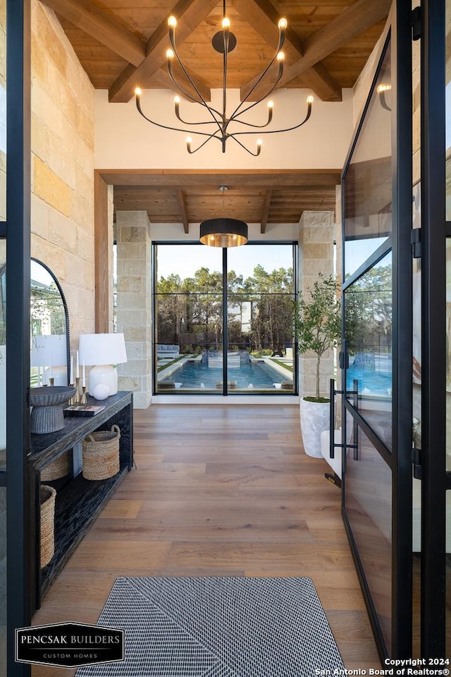 interior space with hardwood / wood-style flooring, a notable chandelier, lofted ceiling with beams, and wood ceiling