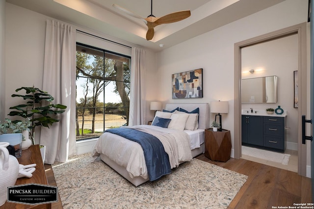 bedroom with hardwood / wood-style flooring, ceiling fan, ensuite bathroom, and multiple windows