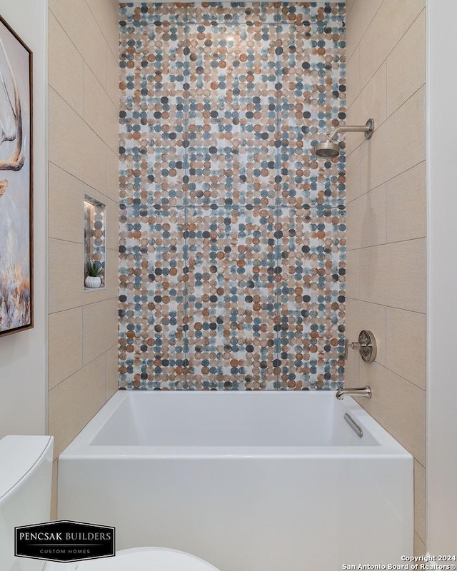 bathroom featuring tiled shower / bath combo and toilet