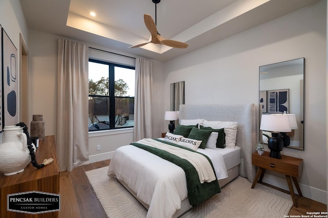 bedroom with a tray ceiling, ceiling fan, and light hardwood / wood-style floors