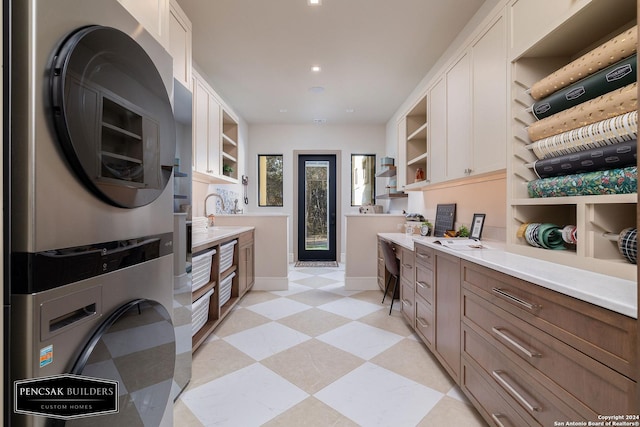 kitchen featuring white cabinets, stacked washing maching and dryer, and sink