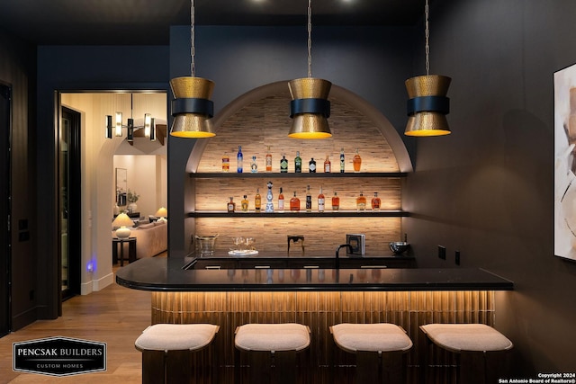 bar with pendant lighting and hardwood / wood-style flooring