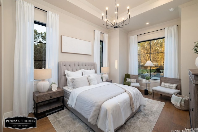 bedroom featuring a tray ceiling, hardwood / wood-style floors, and a notable chandelier