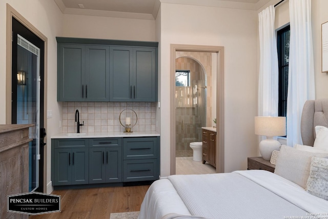 bedroom with ensuite bath, crown molding, light hardwood / wood-style flooring, and sink