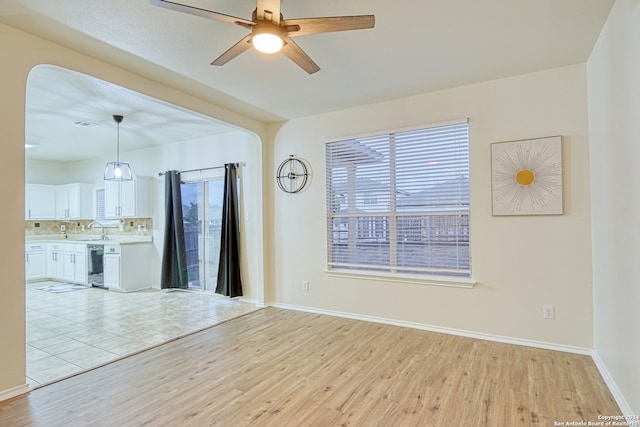 empty room featuring ceiling fan, sink, and light wood-type flooring