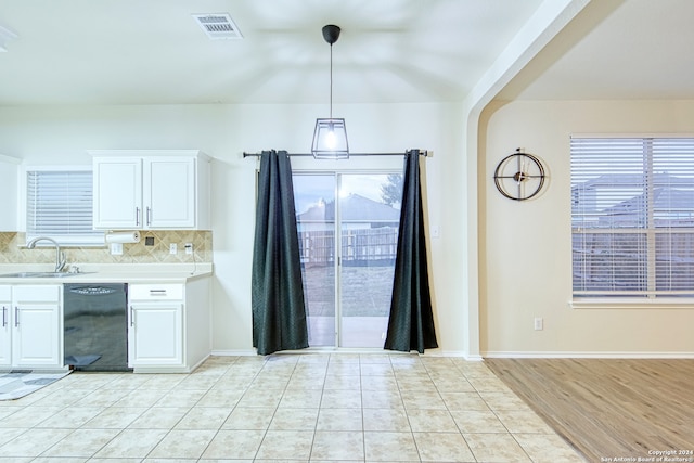 kitchen featuring white cabinetry, sink, hanging light fixtures, and light wood-type flooring