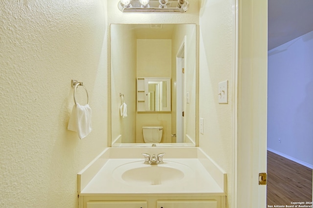 bathroom with hardwood / wood-style floors, vanity, and toilet