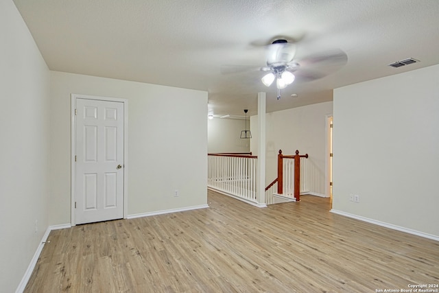 spare room with ceiling fan, light hardwood / wood-style floors, and a textured ceiling