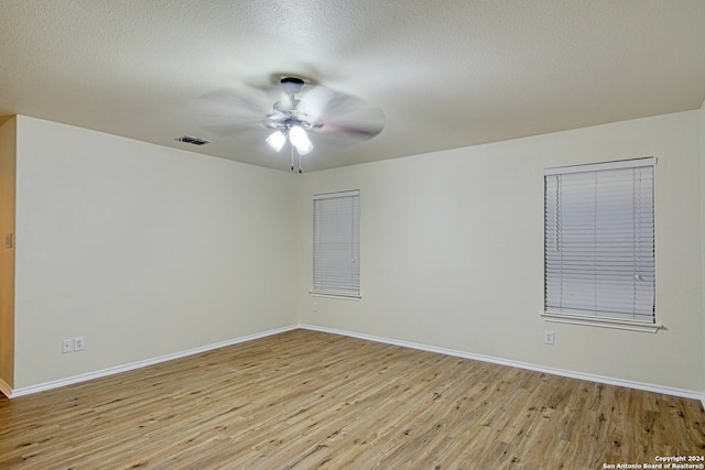 spare room with a textured ceiling, light hardwood / wood-style floors, and ceiling fan