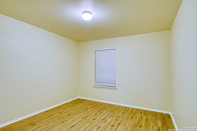 empty room with wood-type flooring and a textured ceiling