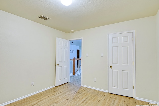 empty room with light hardwood / wood-style flooring and a textured ceiling