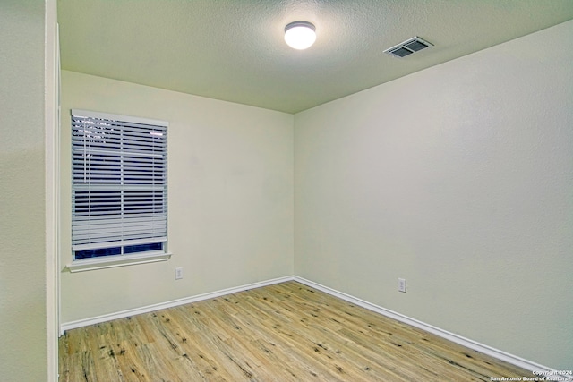 spare room with light hardwood / wood-style floors and a textured ceiling