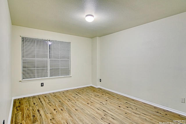 spare room featuring a textured ceiling and light hardwood / wood-style floors