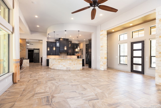 kitchen with light stone countertops, tasteful backsplash, ceiling fan, pendant lighting, and a kitchen island