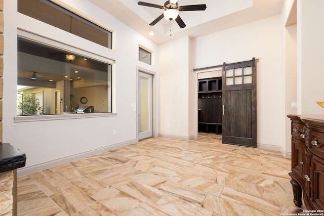 interior space with a barn door and ceiling fan