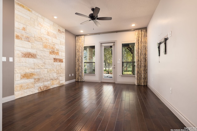 empty room with a textured ceiling, dark hardwood / wood-style flooring, and ceiling fan