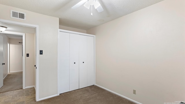 unfurnished bedroom with ceiling fan, light colored carpet, a textured ceiling, and a closet