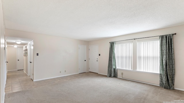 spare room featuring a textured ceiling and light colored carpet