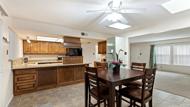 carpeted dining space featuring a textured ceiling, a skylight, ceiling fan, and sink