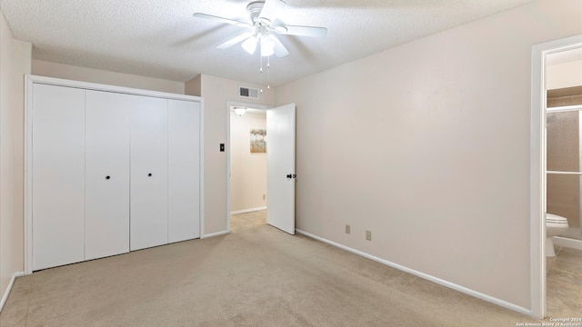 unfurnished bedroom featuring ceiling fan, a closet, ensuite bathroom, and light carpet