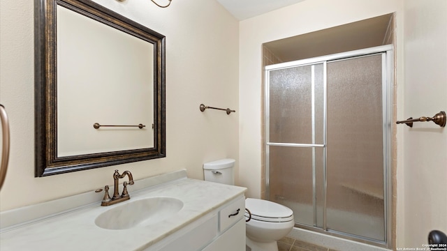 bathroom with tile patterned flooring, vanity, toilet, and a shower with door